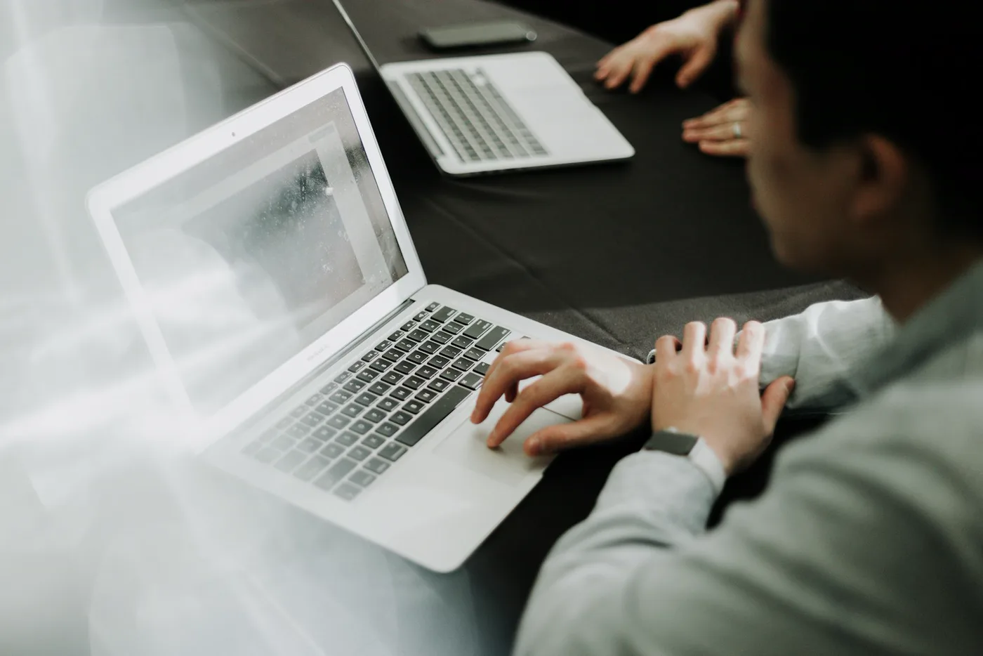 Two people reviewing a plan on laptops across a table
